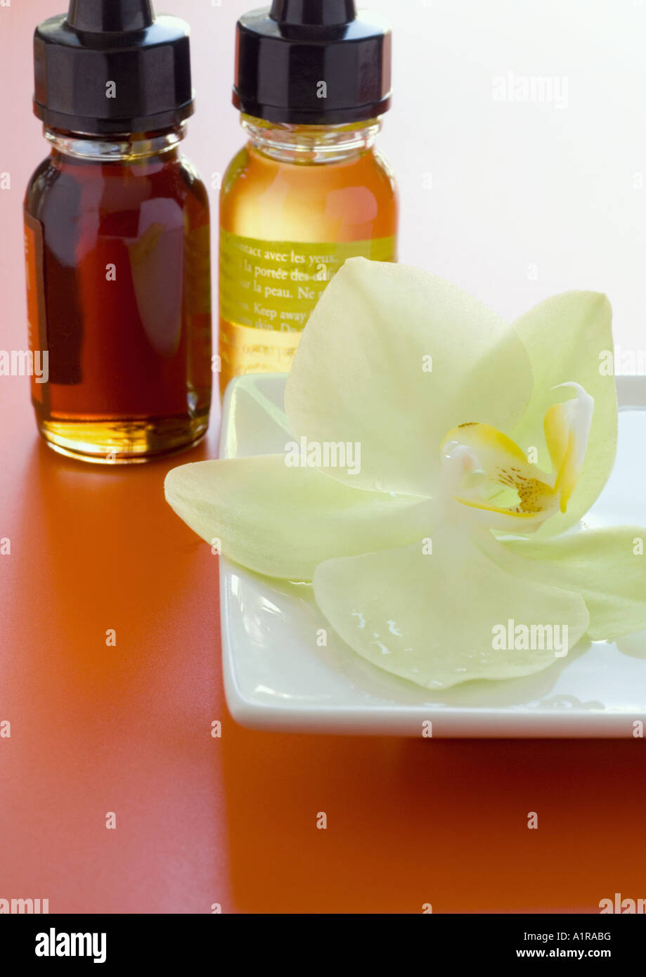 Bottiglie di oli profumati e fioriscono orchidee Foto Stock