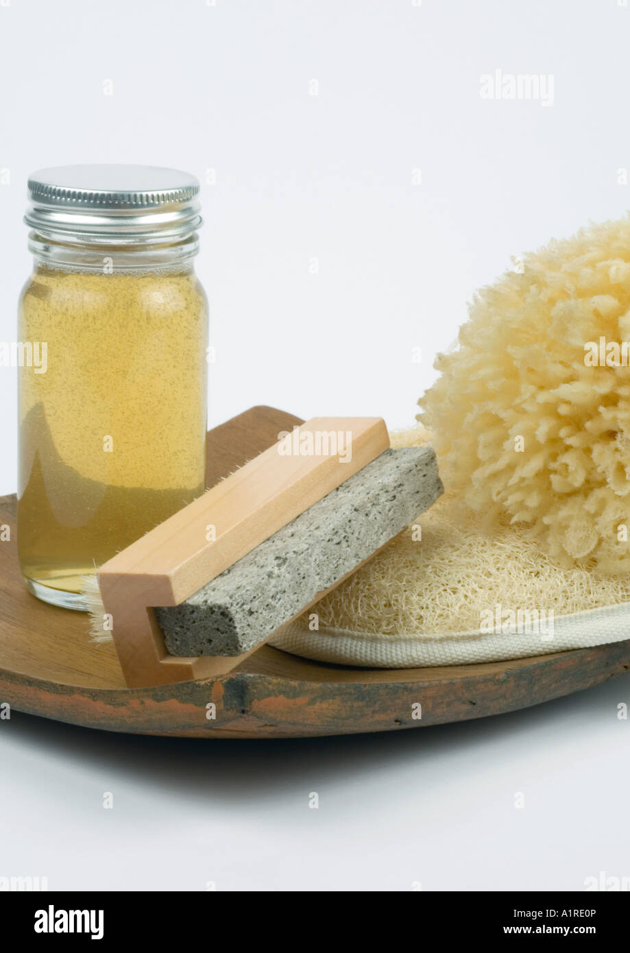 Prodotti di toelettatura, pietra pomice, olio corpo, loofah e spugna sul vassoio in legno Foto Stock