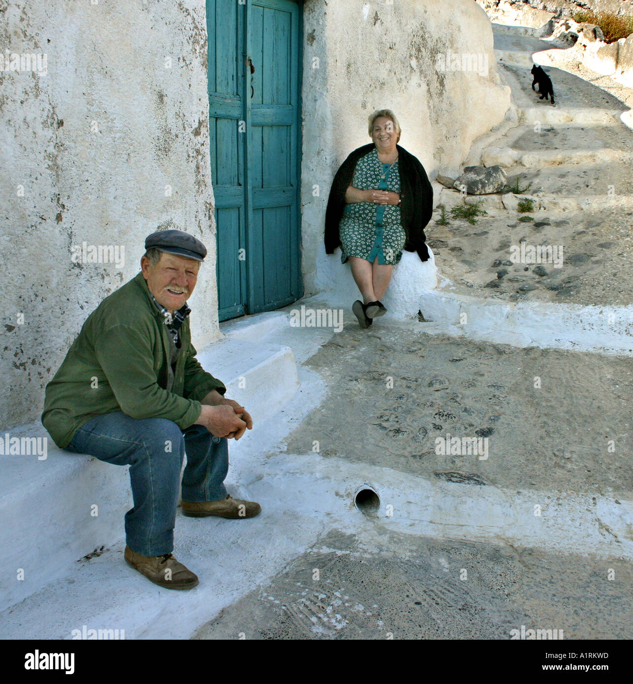 Pomeriggio intimo Chat: un uomo e una donna seduta su ciascun lato di una chiusura sportello blu nella parte anteriore di un bianco lavato house Foto Stock