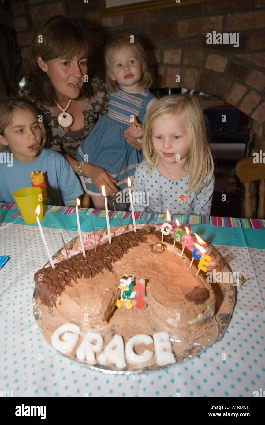 4 anno vecchia ragazza soffiando fuori le candele sul cioccolato torta di compleanno REGNO UNITO Foto Stock
