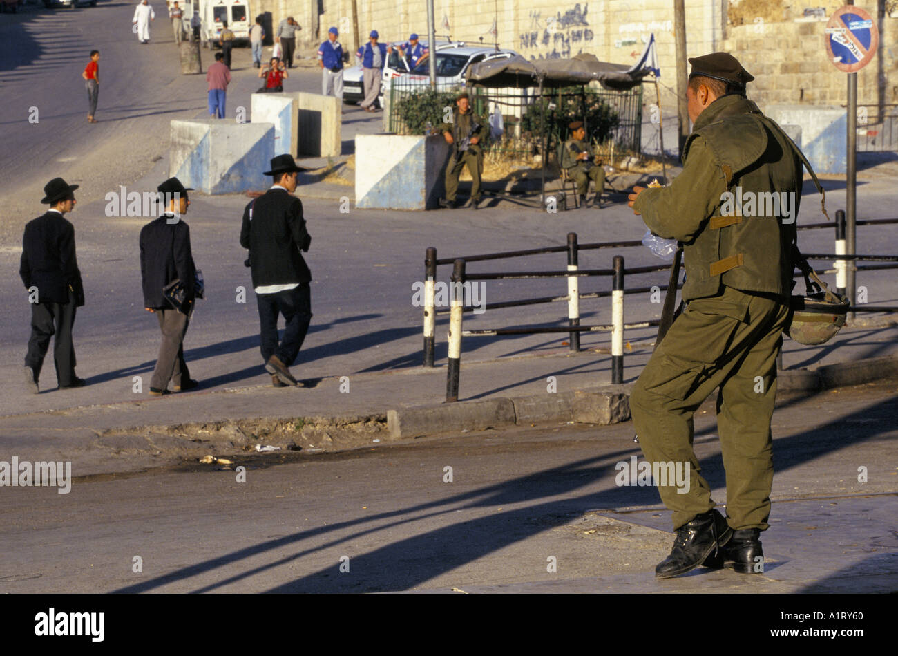 Coloni ebrei in Cisgiordania HEBRON ULTRA ebrei ortodossi a piedi a Hebron guardato da soldati IDF E OSSERVATORI TIPH 1996 Foto Stock