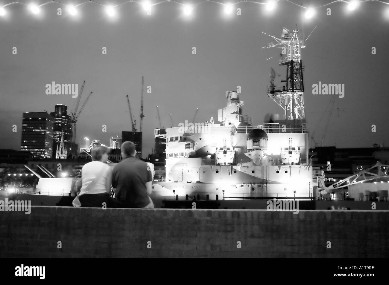 Londra INGHILTERRA, coppia da dietro rilassante sul Tamigi Quai con la nave "HMS Belfast" di notte (foto in bianco e nero) Vista panoramica Foto Stock