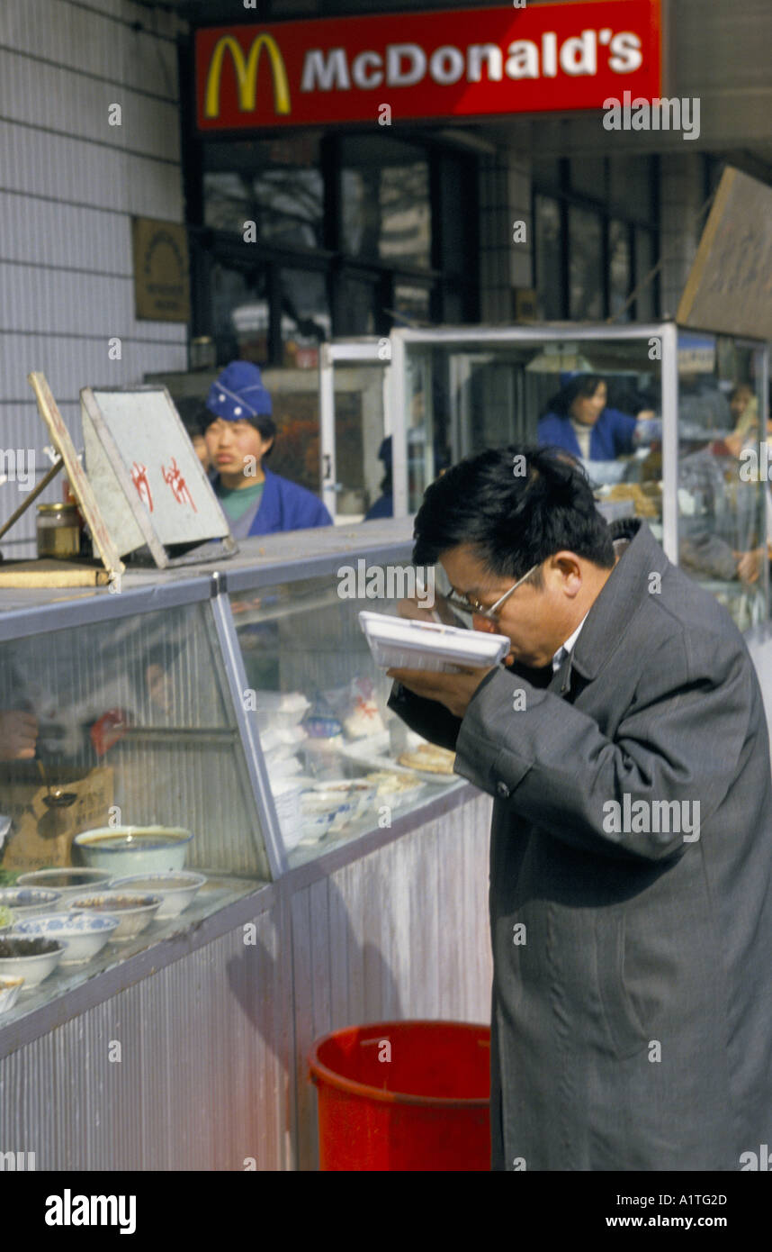 Pechino alba al crepuscolo uomo mangiare cibo cinese al di fuori di MCDONALDS Foto Stock
