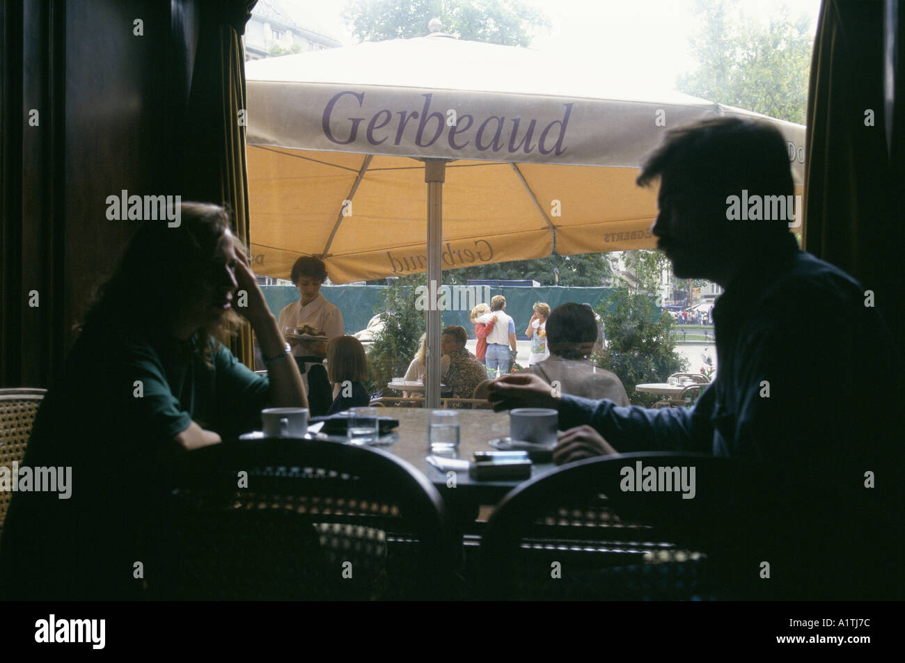 Uomo e donna sedersi dentro il Cafè Gerbeaud di bere il caffè altri clienti sedersi fuori sotto gli ombrelloni Agosto 1995 Foto Stock