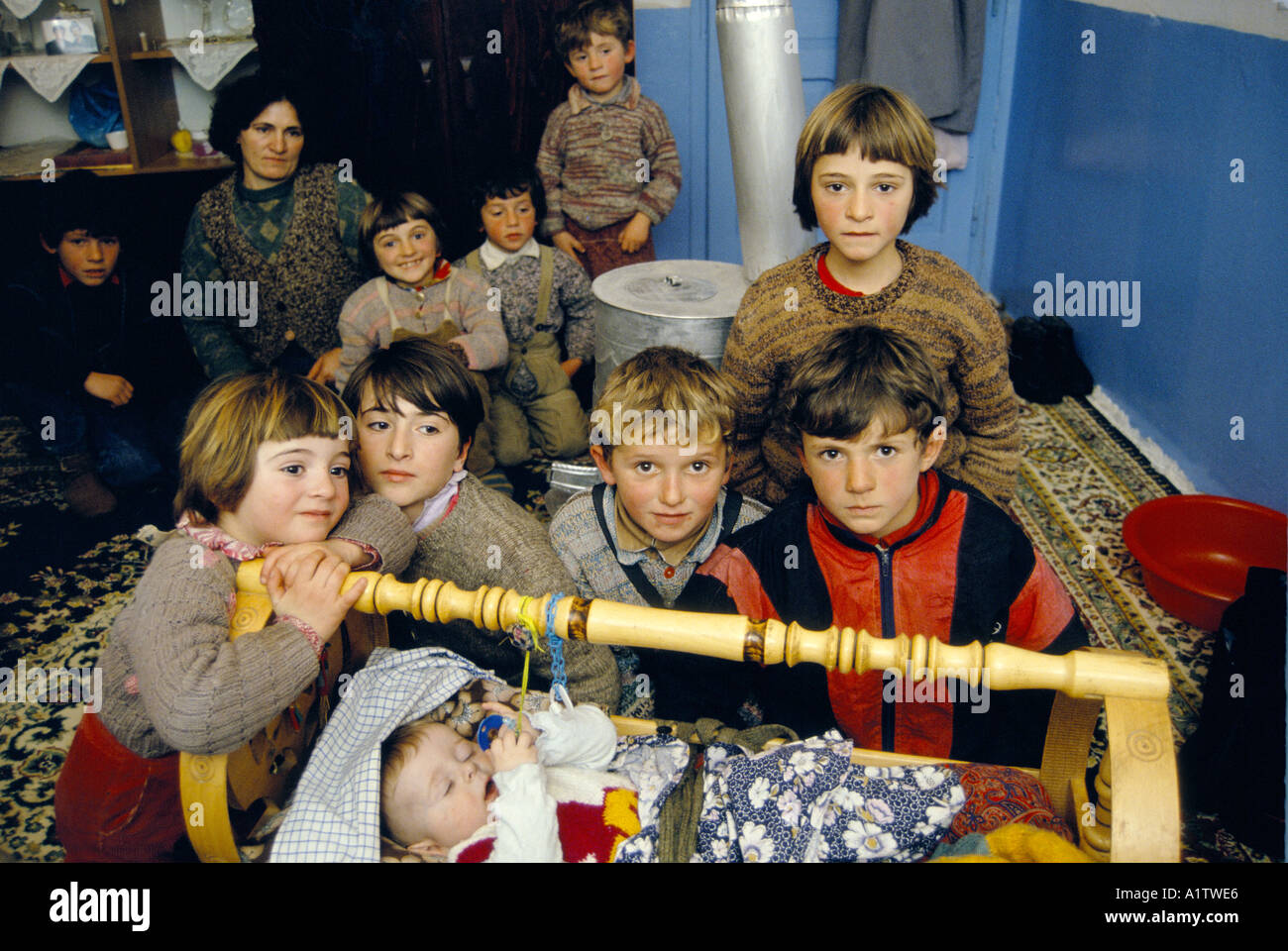 Povera famiglia albanese con un folto gruppo di bambini intorno al bambino  in una culla oscillante Foto stock - Alamy