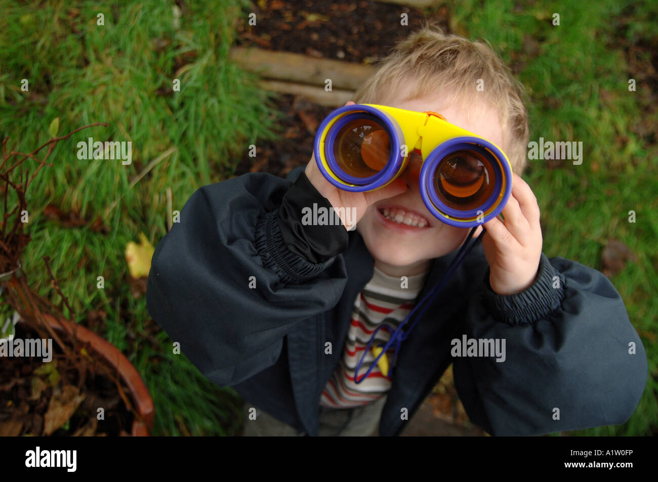 Un giovane ragazzo che guarda attraverso il binocolo Foto Stock