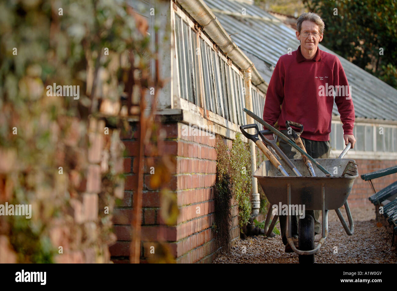 Un giardiniere lavora in un giardino murato in una casa di campagna Foto Stock