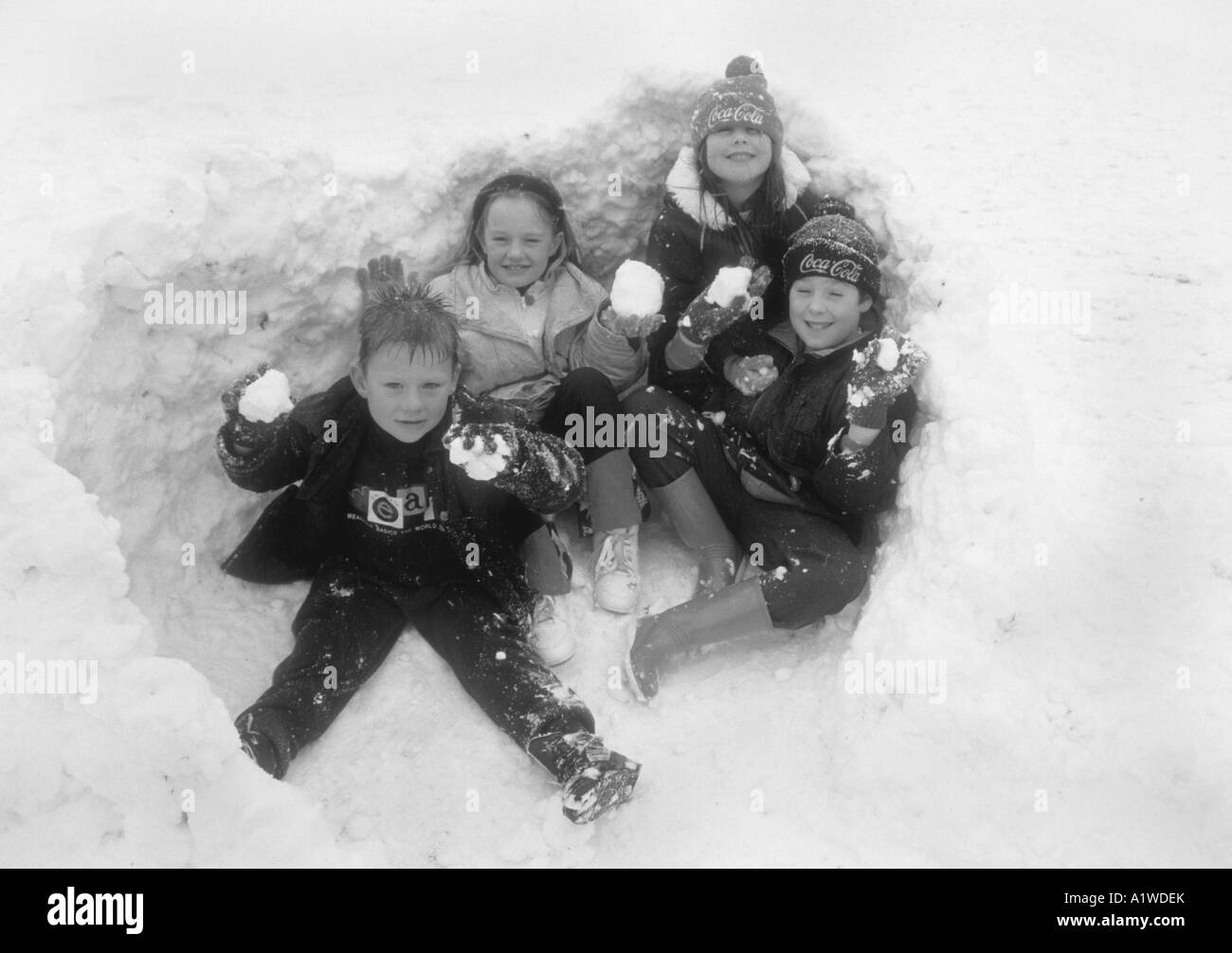 Un gruppo di bambini seduti in un foro,che hanno scavato in paesaggi innevati. Foto Stock