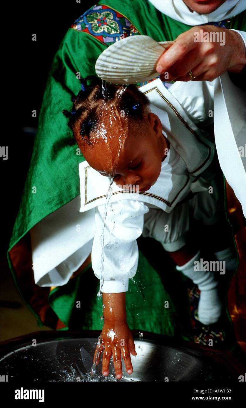 Cristiano protestante Battesimo - vicario versa acqua dal font sopra la testa del bambino essendo battezzato Foto Stock