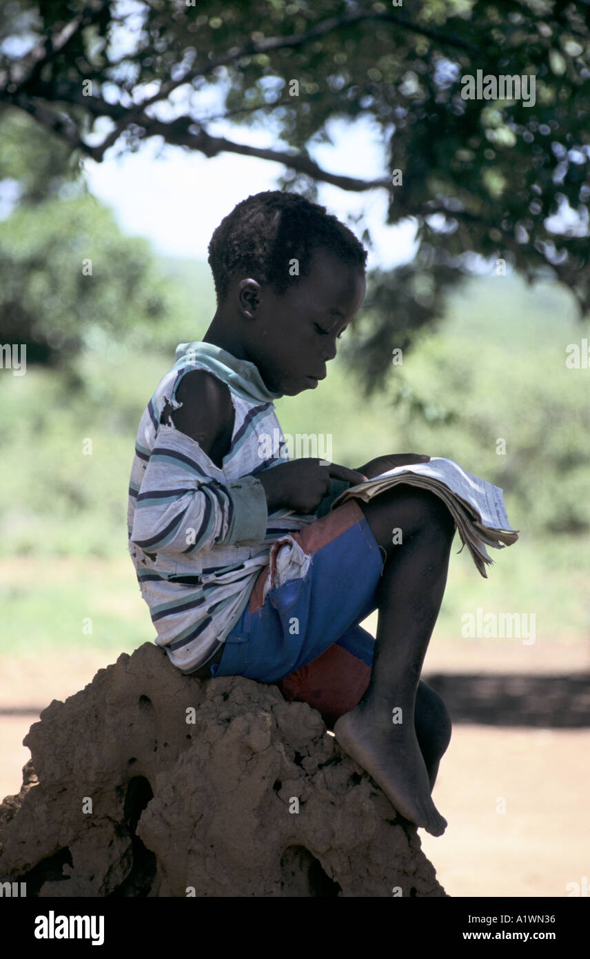 Biddi Biddi scuola Uganda un giovane bambino ,rifugiato sudanese,studiando, seduti su una formica/termite hill Foto Stock