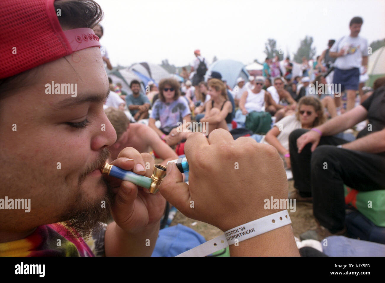 Uomo di fumare marijuana con un tubo Woodstock Music Festival 1994 CONCERTO USA la droga party POT Foto Stock