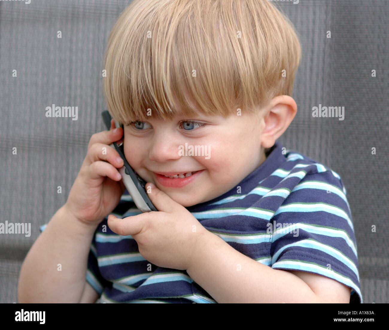 Piccolo bambino parlando su 'telefono cellulare' comunicanti sorridente Foto Stock