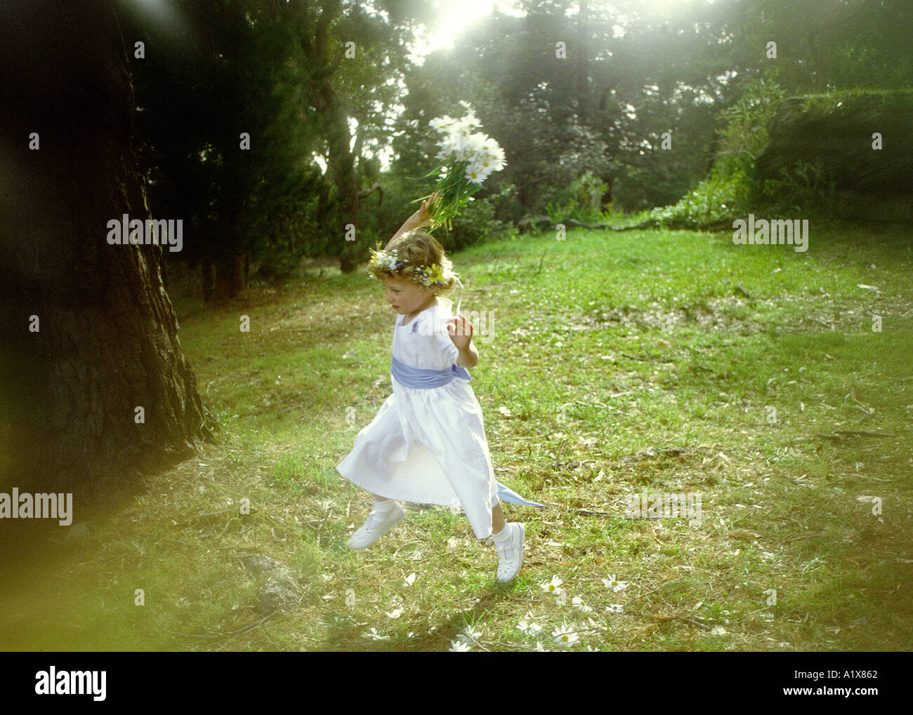 Un piccolo fiore-girl correndo giù per una collina Foto Stock