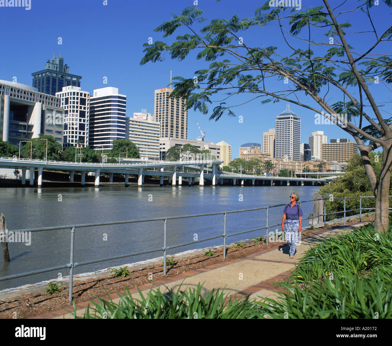 Un turista a camminare accanto al Fiume Brisbane con lo skyline della città dietro a Brisbane Queensland Australia G R Richardson Foto Stock