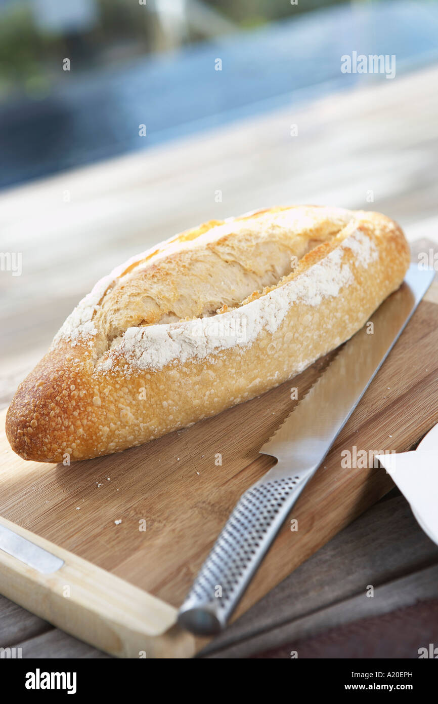 Rotolo di pane sul tagliere sul tavolo da picnic con Coltello per pane Foto Stock