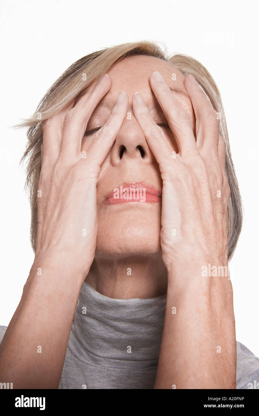 Senior donna con le mani sul viso, close-up Foto Stock