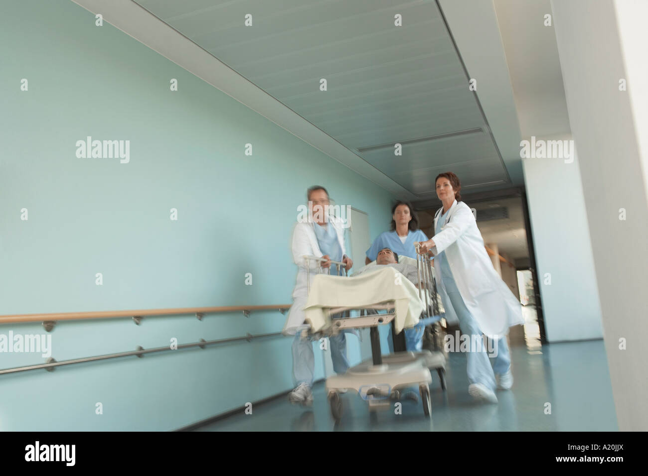 I medici Rushing paziente sulla barella verso il basso corridoio ospedale Foto Stock
