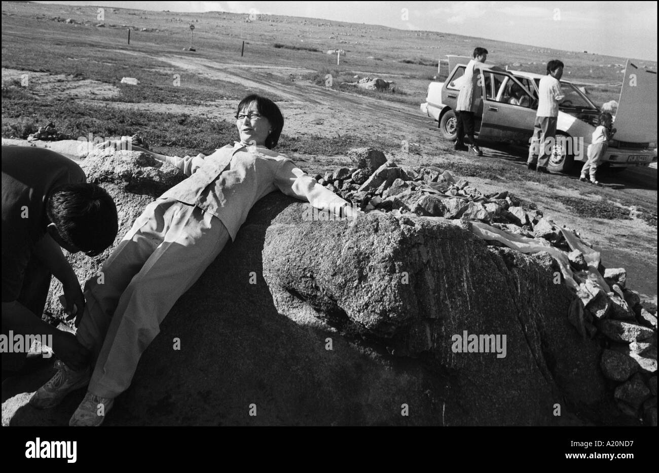 Donna sdraiata su una piccola roccia, vicino la pagoda azienda madre di roccia, Mongolia steppe Foto Stock