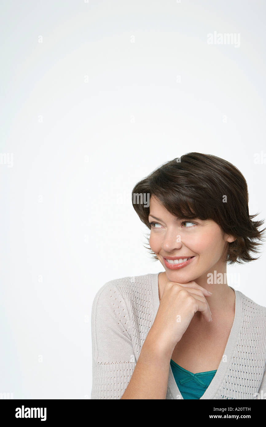 Donna sorridente guardando al lato, mano sul mento Foto Stock