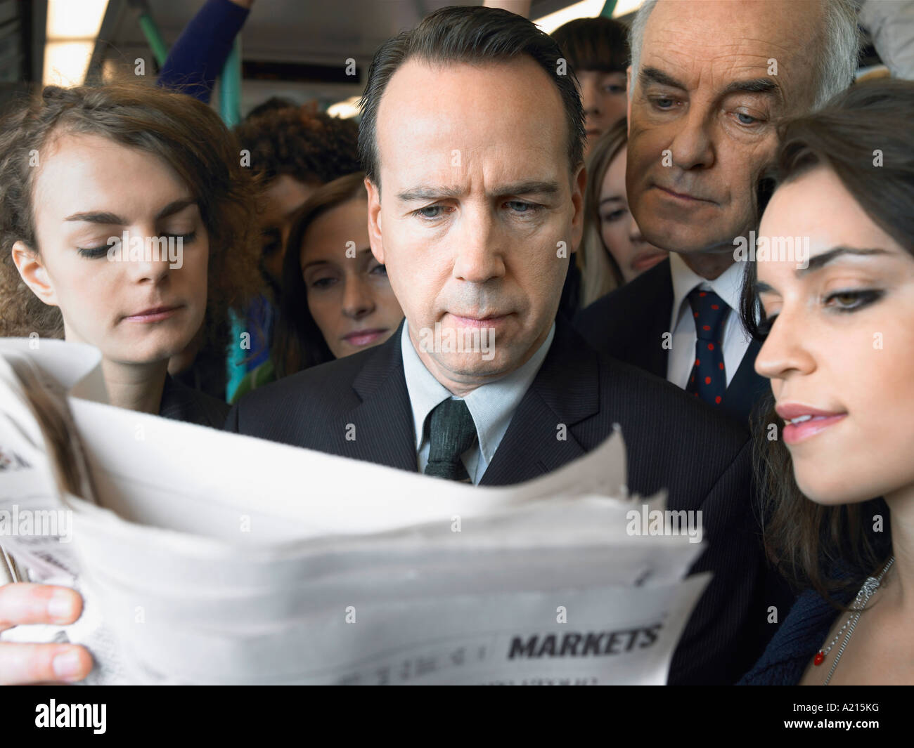 Pendolari in piedi sul treno, leggendo il giornale sulla spalla Foto Stock
