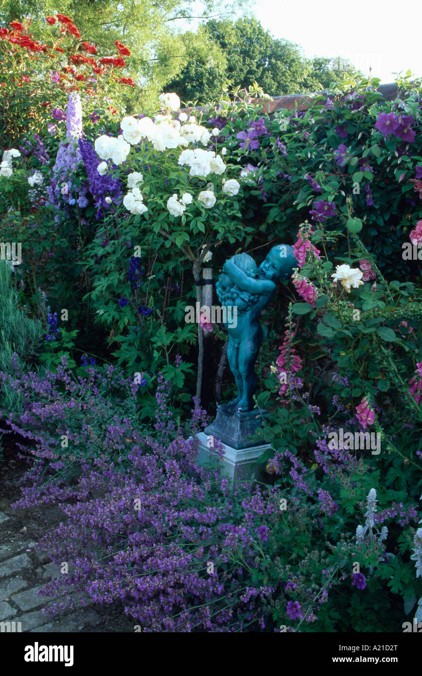 Nepeta sotto la statua in estate confine di rose bianche e blu delphiniums in walled garden Foto Stock
