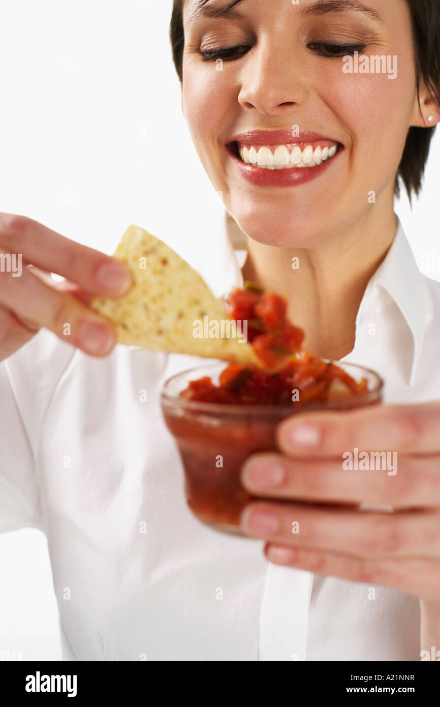 Donna di mangiare la Salsa e Nachos Foto Stock