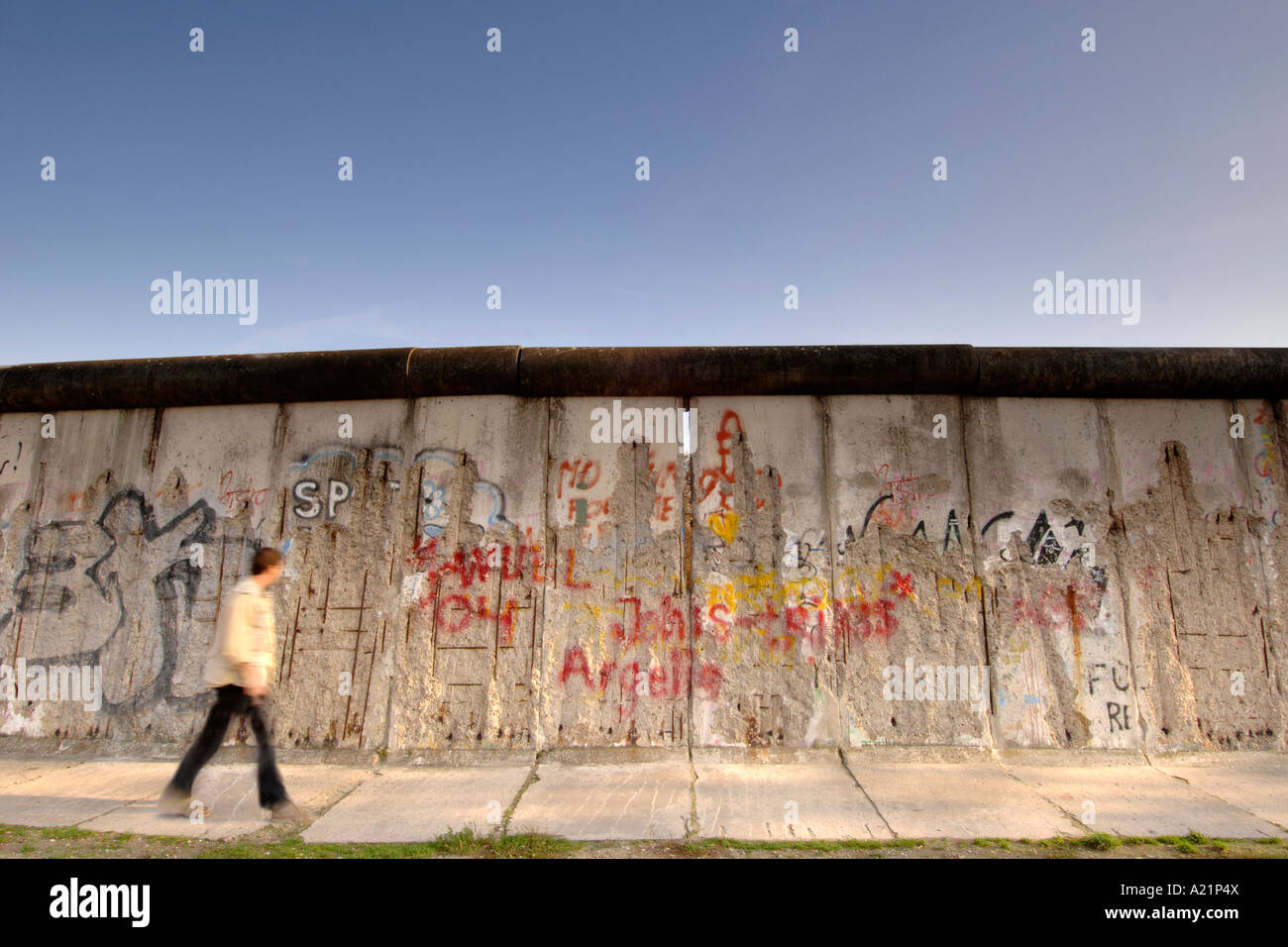 Un uomo cammina oltre il muro di Berlino lungo Bernauer Straße a Berlino Est della Germania. Foto Stock