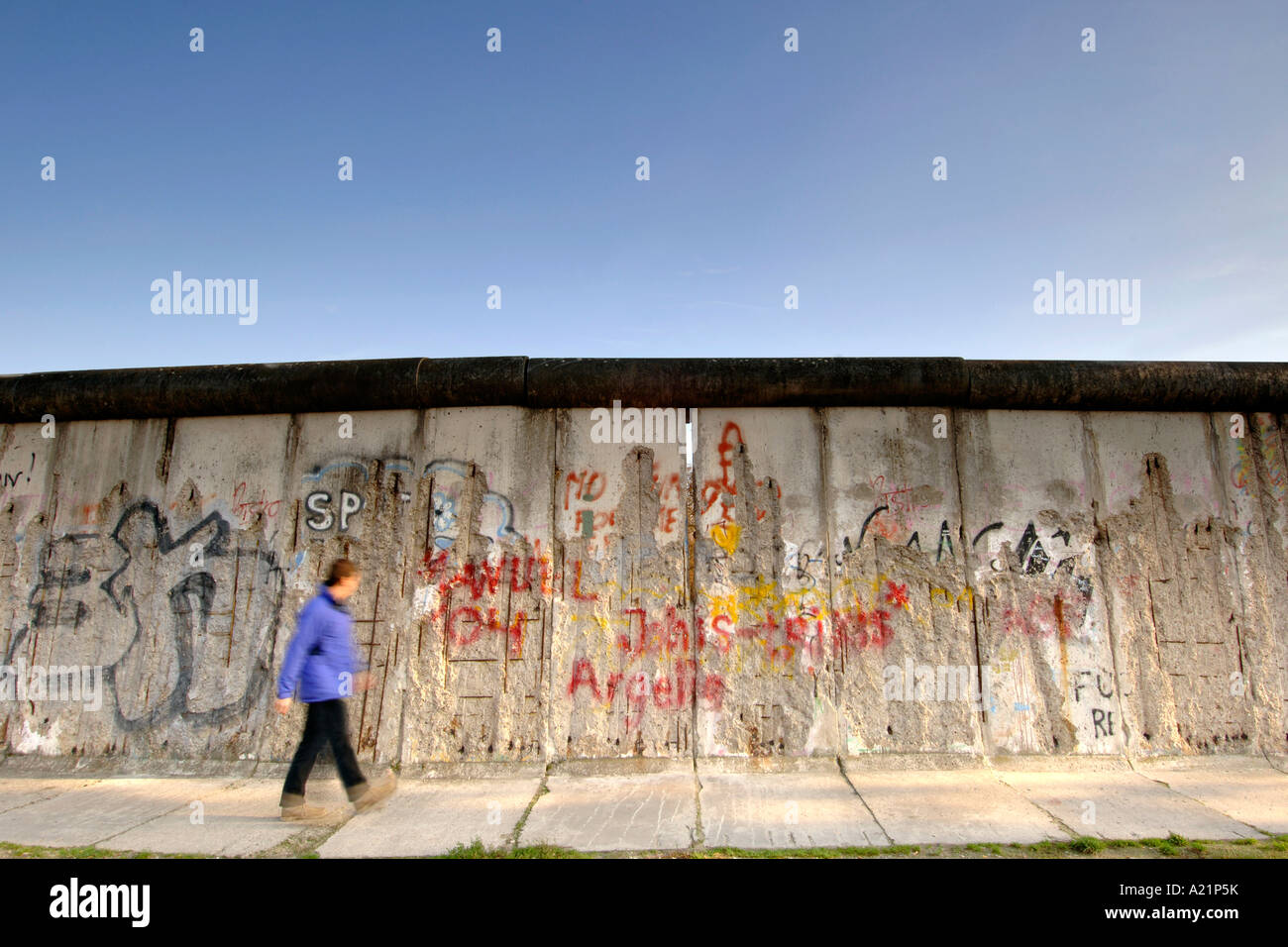 Un uomo cammina oltre il muro di Berlino lungo Bernauer Straße a Berlino Est della Germania. Foto Stock