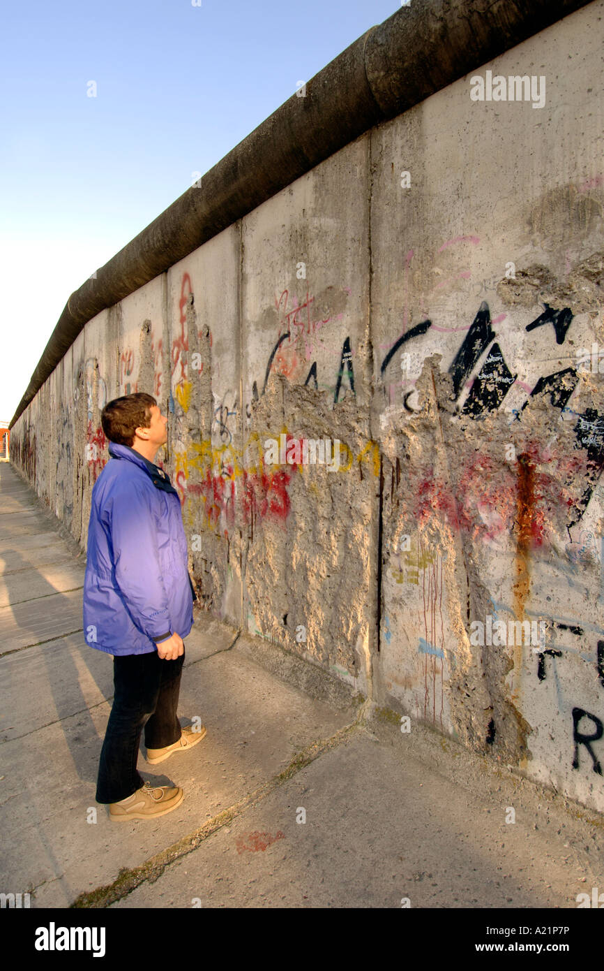 Un uomo la lettura di graffiti sul muro di Berlino lungo Bernauer Straße a Berlino Est della Germania. Foto Stock