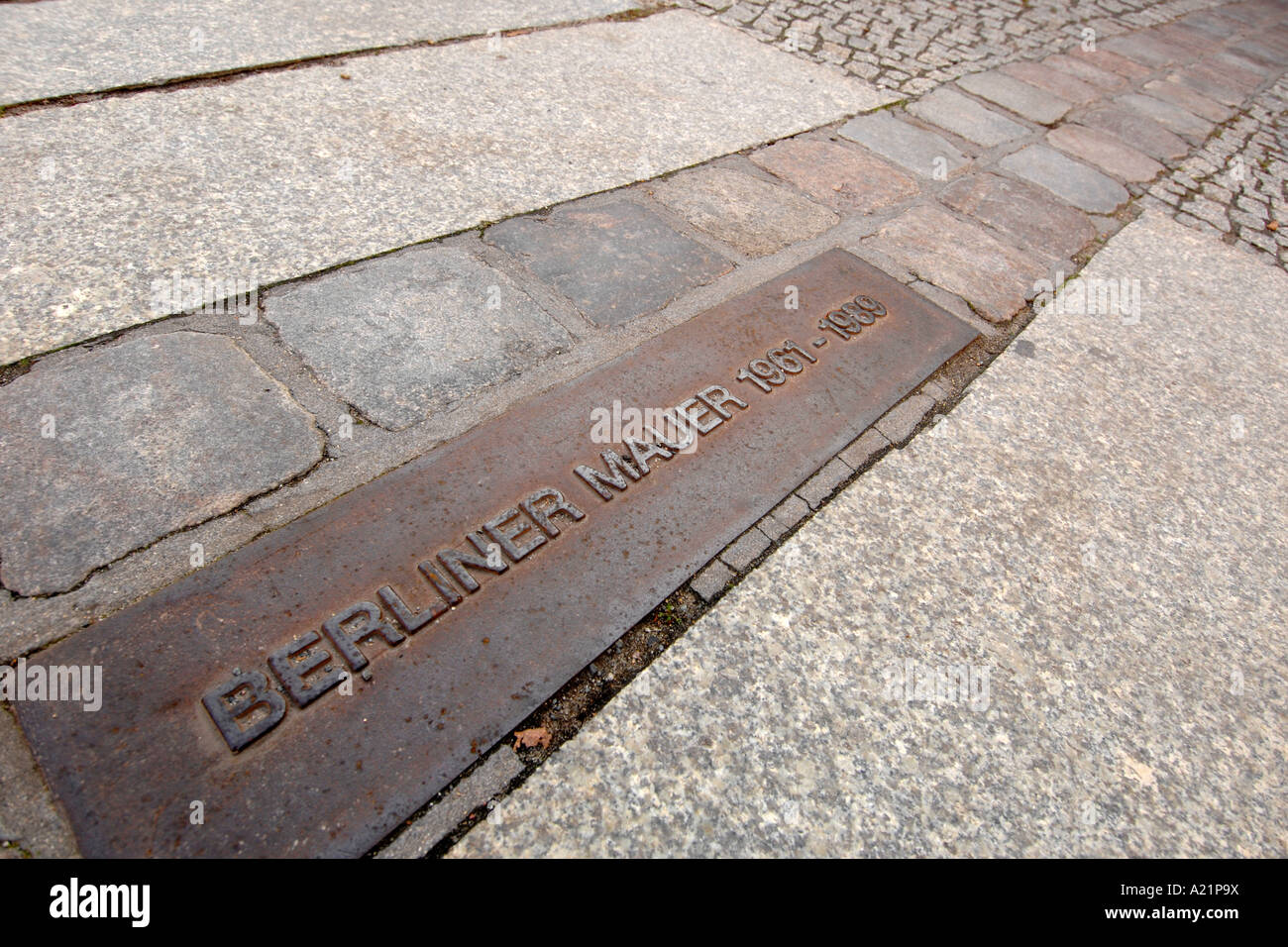 Una lapide commemorativa e la linea di doppio pietre per pavimentazione segnando il vecchio percorso del Muro di Berlino in Germania. Foto Stock
