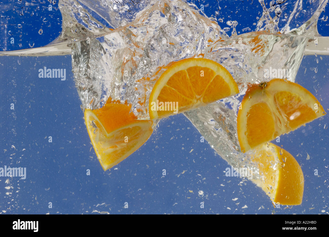 Frutta di arancia gocciolata in acqua facendo splash Foto Stock