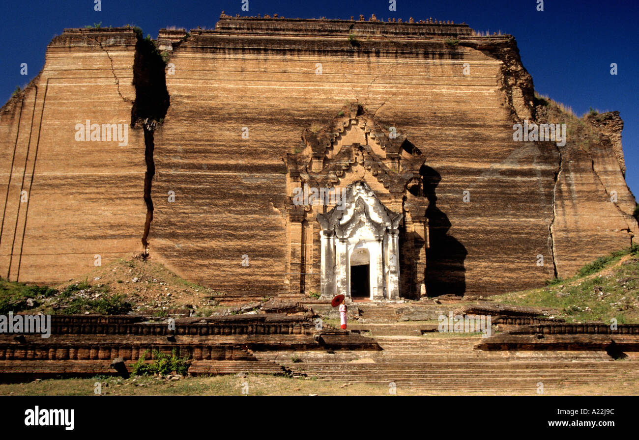 Giovane suora in rosa accappatoi sfumature la sua testa rasata dal sole con un ombrellone presso la storica terremoto danneggiato Pagoda Mingun,Mandalay Foto Stock
