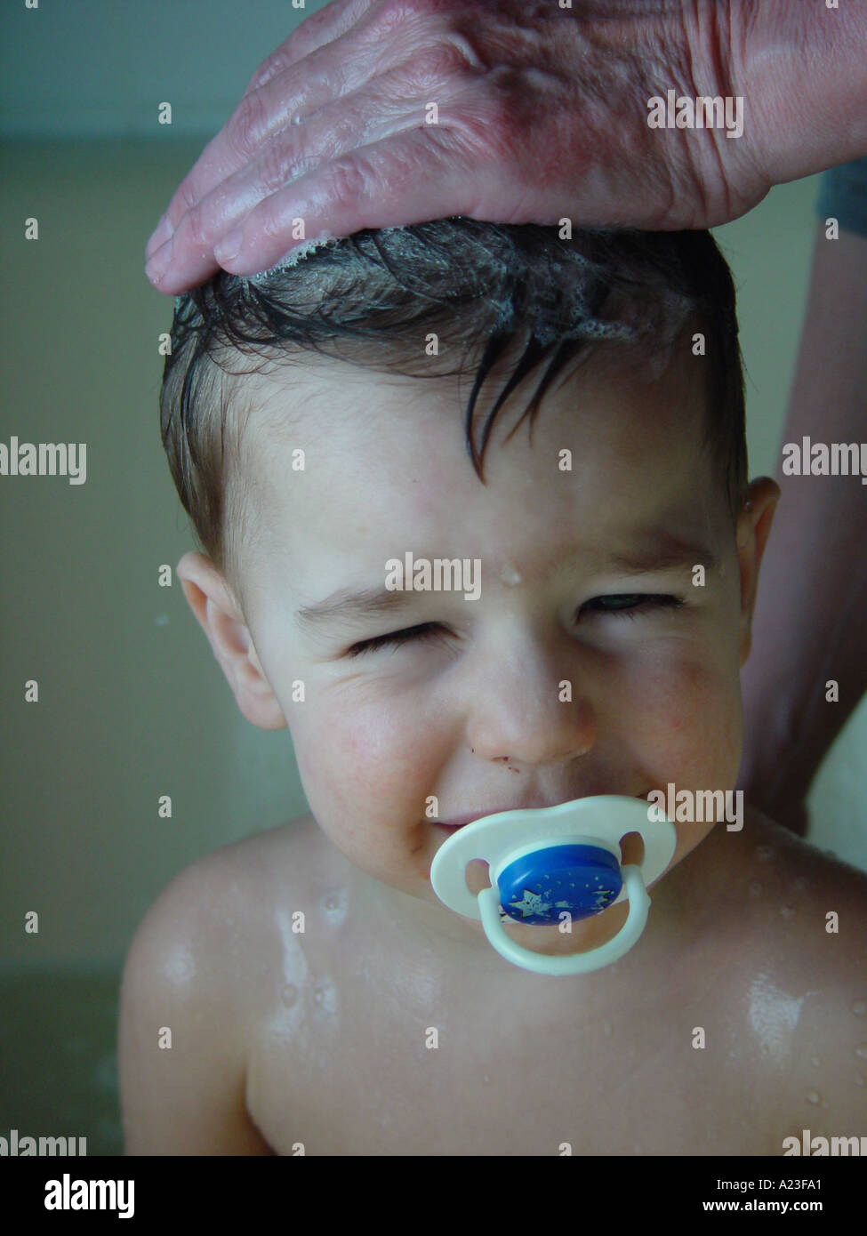 Lavare i capelli del ragazzo dalla madre nella vasca da bagno a casa - bambino con succhietto (non come lavare capelli) Foto Stock