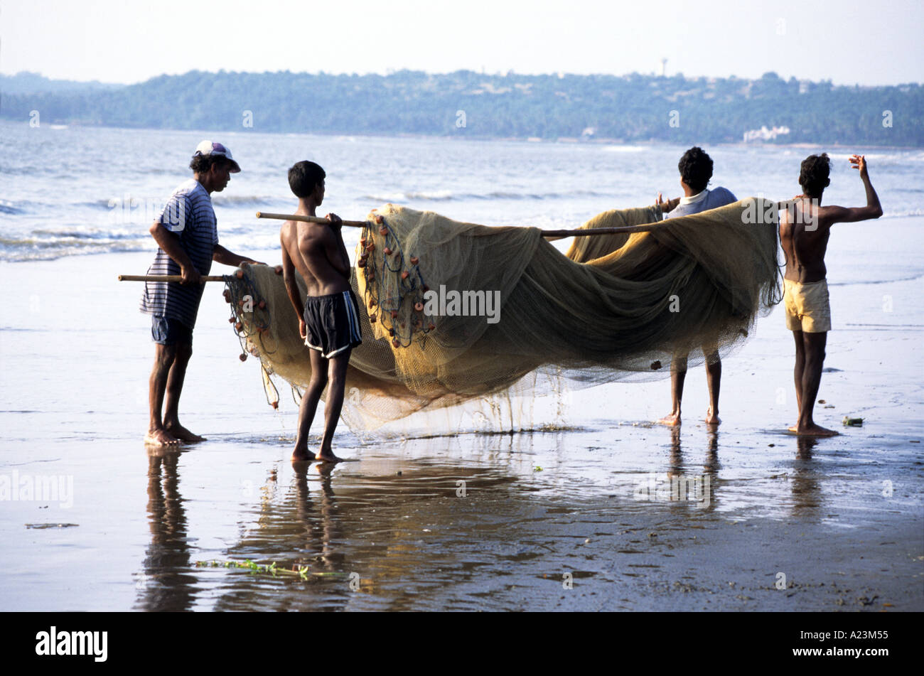 I pescatori raccogliendo le reti da pesca su una spiaggia a Goa in India meridionale dopo la pesca di mattina Foto Stock