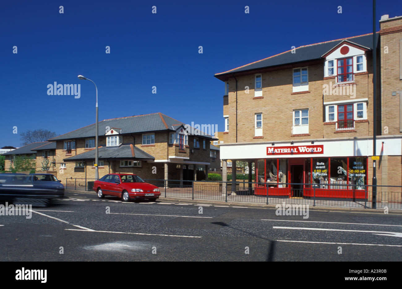 Suburbia High Street con un contenitore di sviluppo e il negozio mondo materiale a Teddington Middlesex London Foto Stock