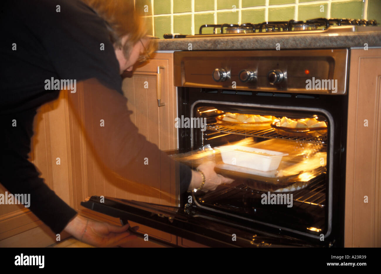 La donna il controllo di un pasto a base di patate arrosto e un dado focaccia nel contenitore in plastica in forno Foto Stock