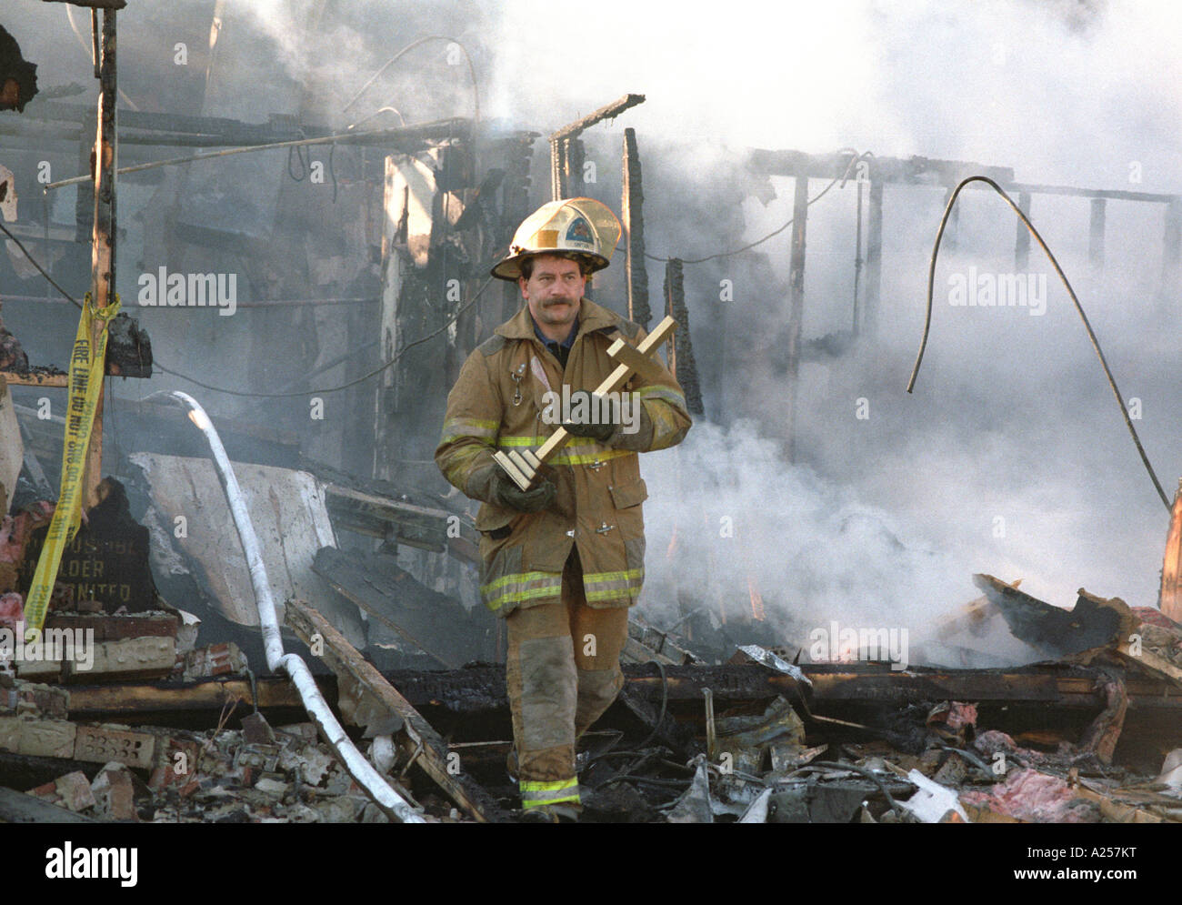 Vigile del fuoco porta una croce al di fuori del bruciato le rovine di una chiesa battista in Bowie Md USA Foto Stock