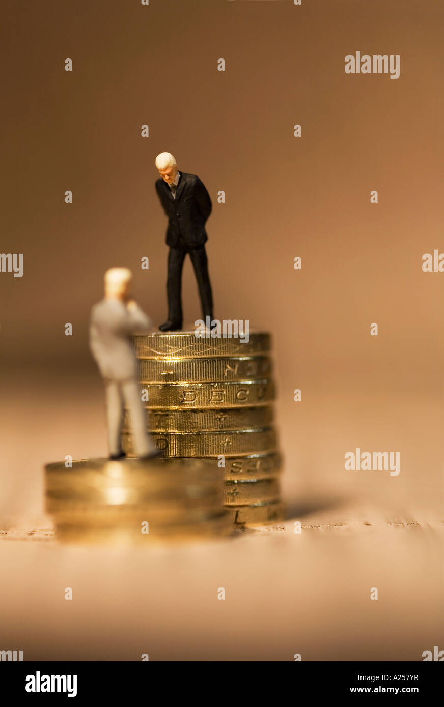 Gli imprenditori in miniatura in piedi sulle monete sul quotidiano finanziario Foto Stock