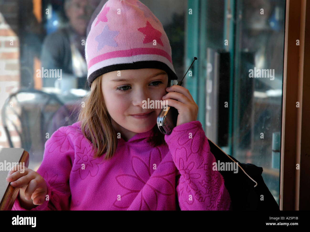 Una bambina di cinque anni in toque calza il cappello e maglietta viola ascoltando la sua madre sul telefono cellulare Foto Stock
