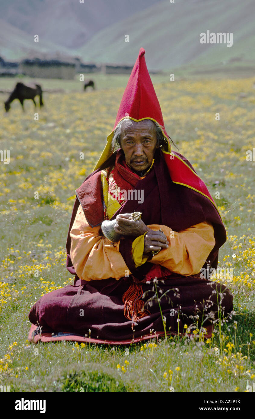 Capo monaco del monastero JAGLUNG detiene una campana e dorje in un fiorito campo himalayana DO TARAP VALLEY QUARTIERE DOLPO NEPAL Foto Stock