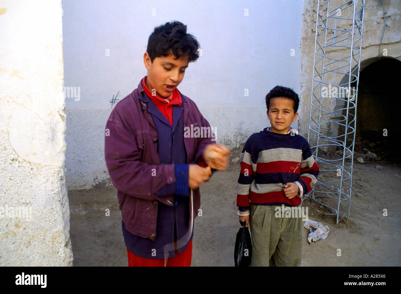 Nefta Tunisia giovane ragazzo adolescente e giovane ragazzo giocando con cime di filatura Foto Stock