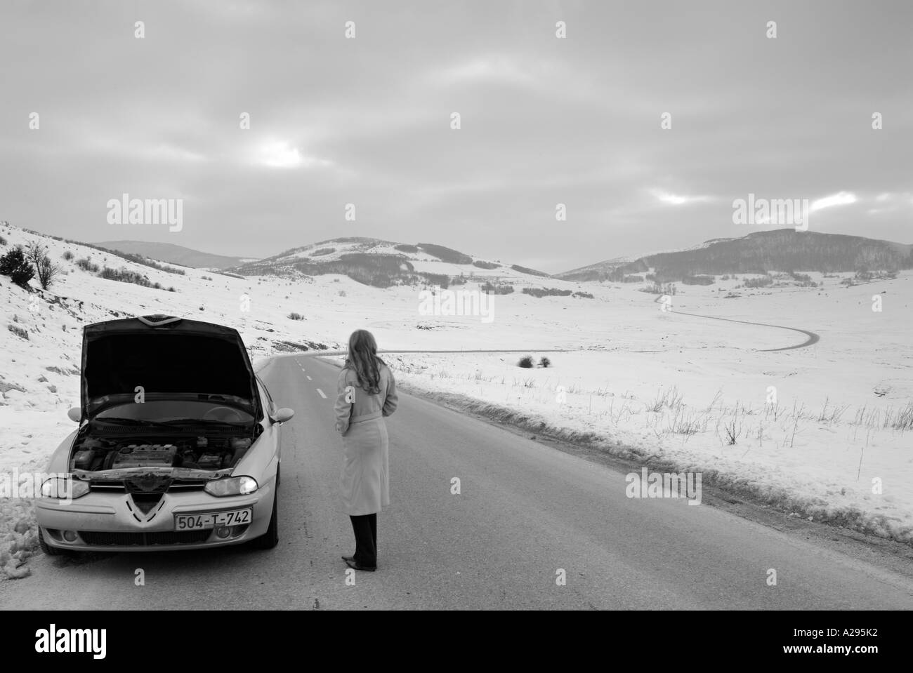 Donna arenati su una strada isolata in inverno dopo la sua auto Breaksdown Foto Stock