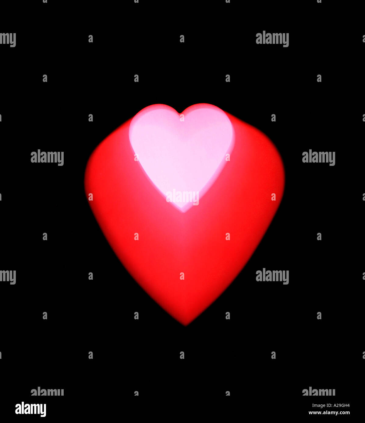 Cuore rosa all'interno di un cuore rosso su sfondo nero Foto Stock