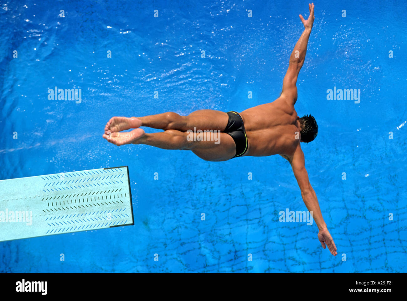 Vista aerea di un maschio di trampolino di lancio subacqueo formando un crocifisso forma come si immerge nella piscina durante un tuffo Foto Stock