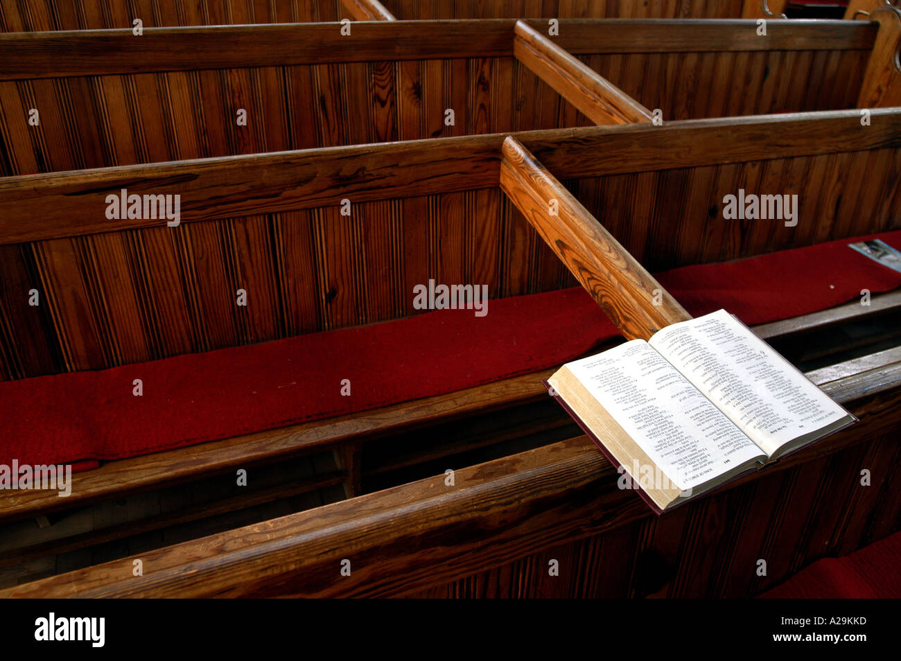 Una Bibbia in appoggio sui banchi vuoti posti in una chiesa, che illustra come un minor numero di persone stanno usando la chiesa Foto Stock