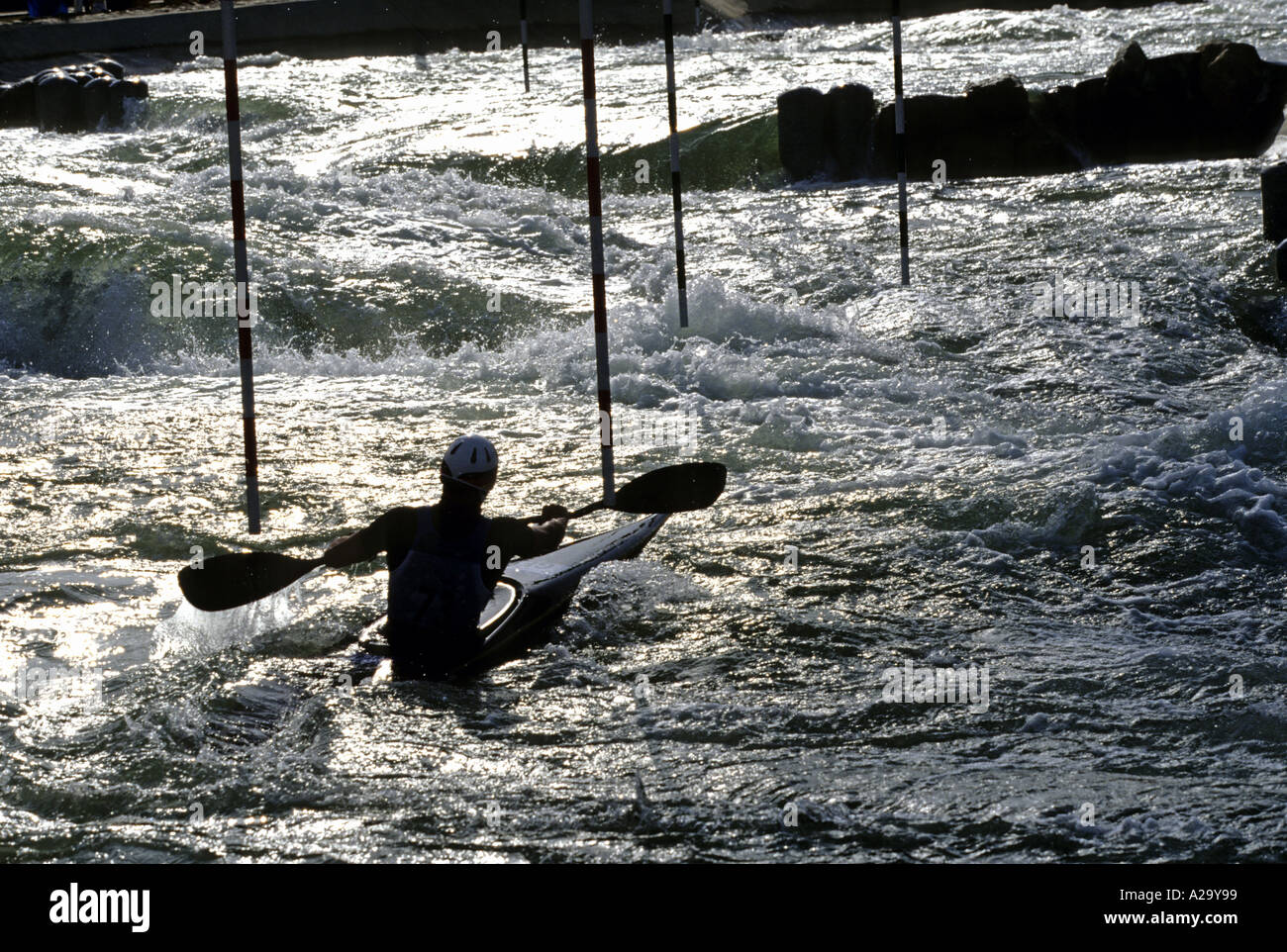 Un maschio di kayak slalom concorrente stagliano veloce che scorre acqua bianca la navigazione tra i poli Foto Stock