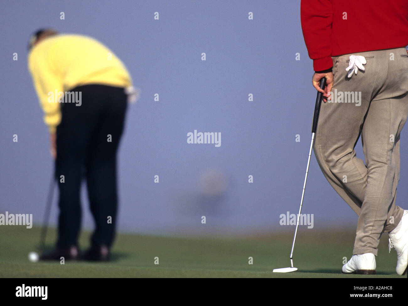 Close up di un golfista appoggiano sul suo putter come suo partner riproduzione putts sul verde dietro a St Andrews in Scozia Foto Stock