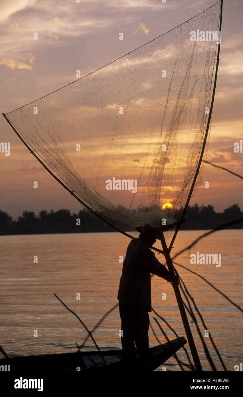 Pescatore sulla prua di una piccola barca con una grande rete da pesca. Il fiume Mekong, Cambogia. Foto Stock