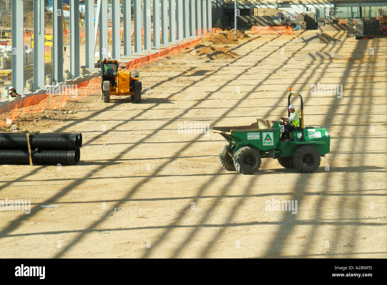 Costruzione nuovo grande magazzino edificio sviluppo sito dumper macchina funzionante al di sotto di unclad quadro siderurgico gettando ombre England Regno Unito Foto Stock