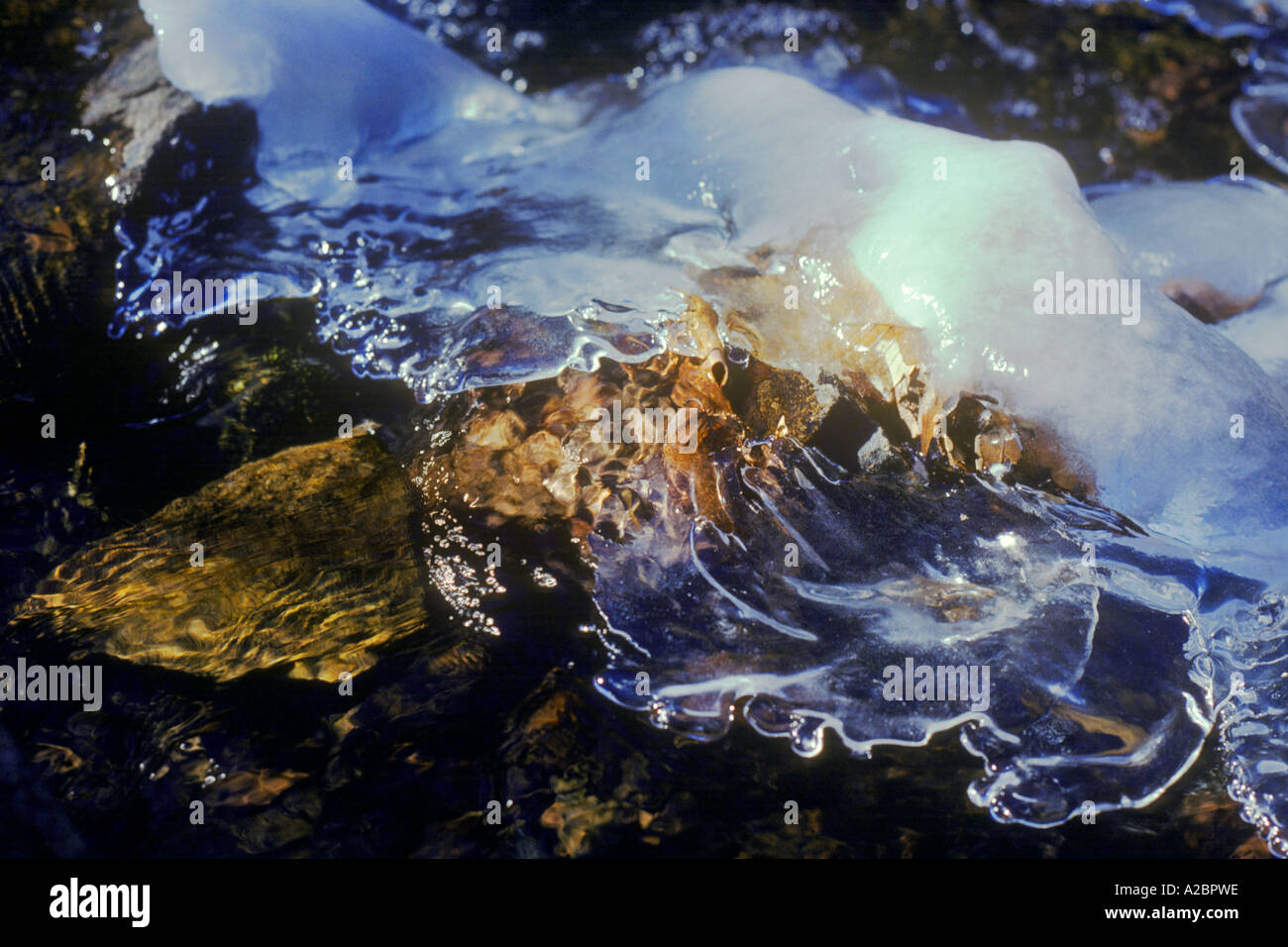 Acqua fluente. Cambiamenti climatici. Riscaldamento globale. Ghiaccio sottile trasparente sulle rocce in un ruscello. Restringimento del closeup del ghiaccio di fusione. Fragilità della natura Foto Stock